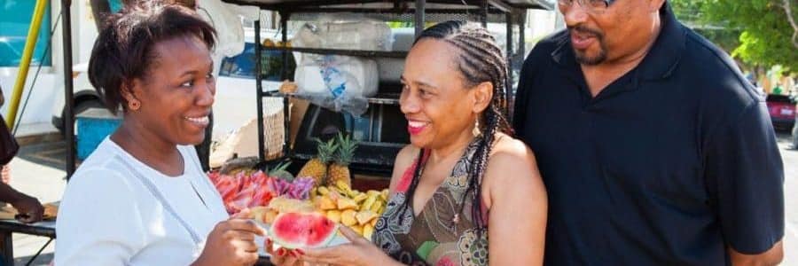 Student couple on tour Tipico Dominicano at a fruit stand with their Spanish teacher.