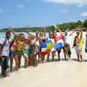 For the new Spanish Course program a group of Spanish students stands on the beach of Punta Rucia during one of IIC Spanish School's social activities, waving the Dominican flag, having fun, and enjoying their time together, experiencing the Dominican Republic's beautiful beaches and the great hospitality of its people while learning Spanish in the Dominican Republic.