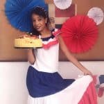 Berenice in traditional Dominican clothing from IIC Spanish School Dominican Republic shows a very special cake made of plantains prepared by students and staff during the Dominican cooking activity at the school.