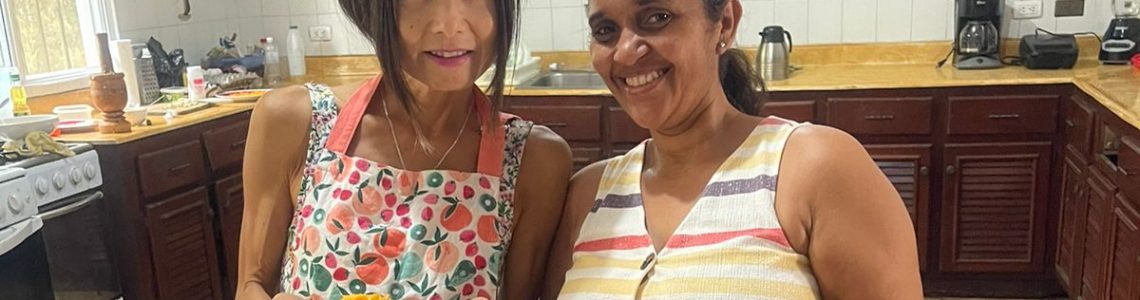 Japanese student and her Spanish teacher in the kitchen of IIC Spanish School Sosua Dominican Republic add flavor to their Dominican cooking, showing their ready-to-eat plates with delicious Dominican food.