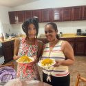 Japanese student and her Spanish teacher in the kitchen of IIC Spanish School Sosua Dominican Republic add flavor to their Dominican cooking, showing their ready-to-eat plates with delicious Dominican food.